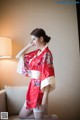 A woman in a red kimono sitting on a couch.