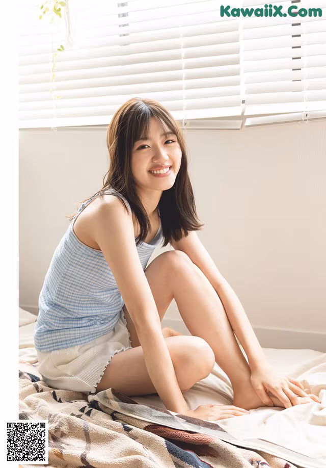 A woman sitting on top of a bed next to a window.