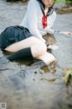 A woman in a school uniform is sitting in the water.