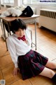 A woman in a school uniform sitting on the floor.