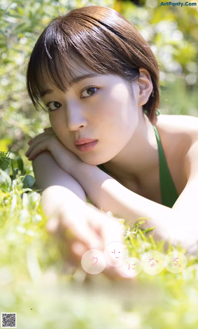 A woman in a green bikini laying in the grass.
