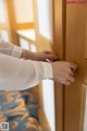 A man in a white shirt is opening a wooden door.