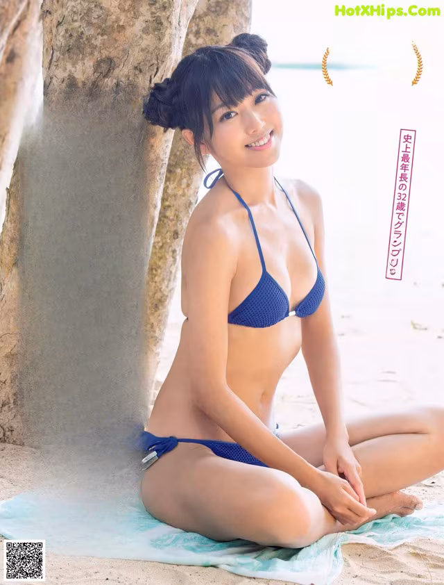 a woman in a blue bikini sitting on a towel on the beach