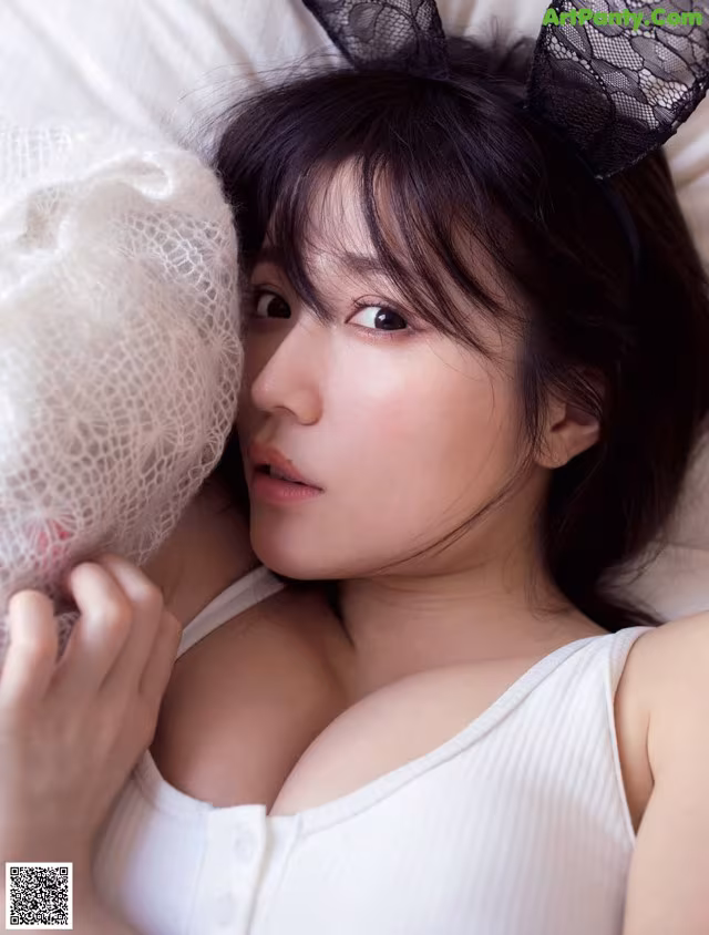 A woman laying in bed with bunny ears on her head.