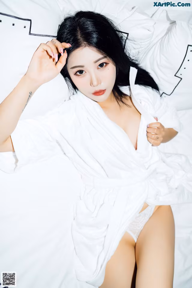 A woman in a white robe laying on a bed.
