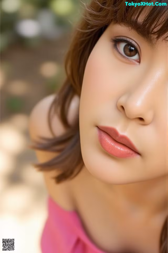 A close up of a woman's face with a pink dress.