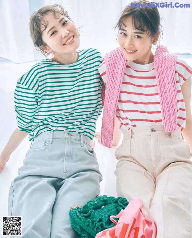 Two young women sitting next to each other on a bed.
