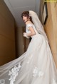 A woman in a wedding dress leaning against a wall.