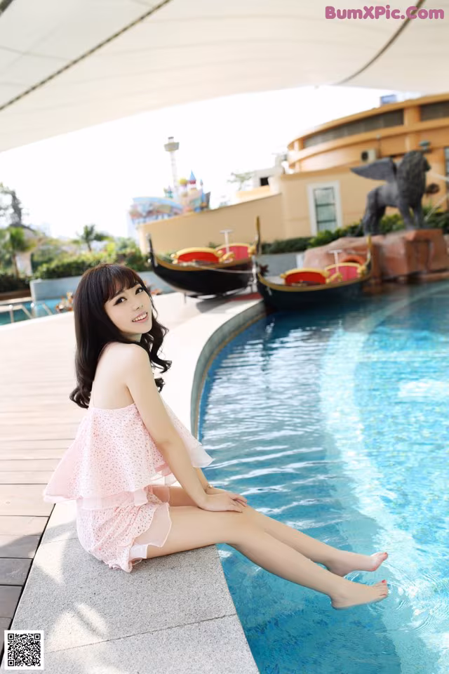A woman sitting on the edge of a swimming pool.