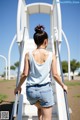 A woman in a white tank top and denim shorts is walking up some stairs.