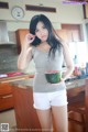 A woman holding a watermelon in a kitchen.